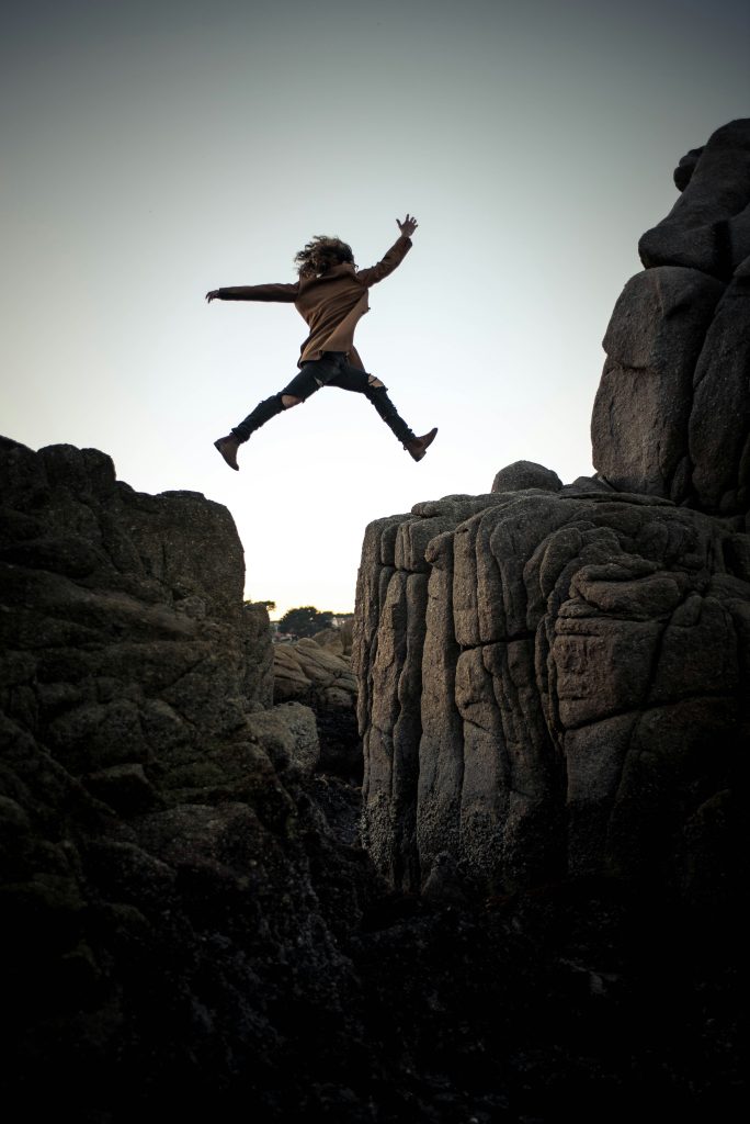 Woman leaping across gap in rocks 